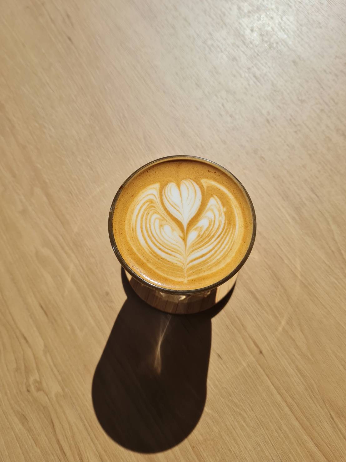 Tulip latte art in a glass cup on a wooden table