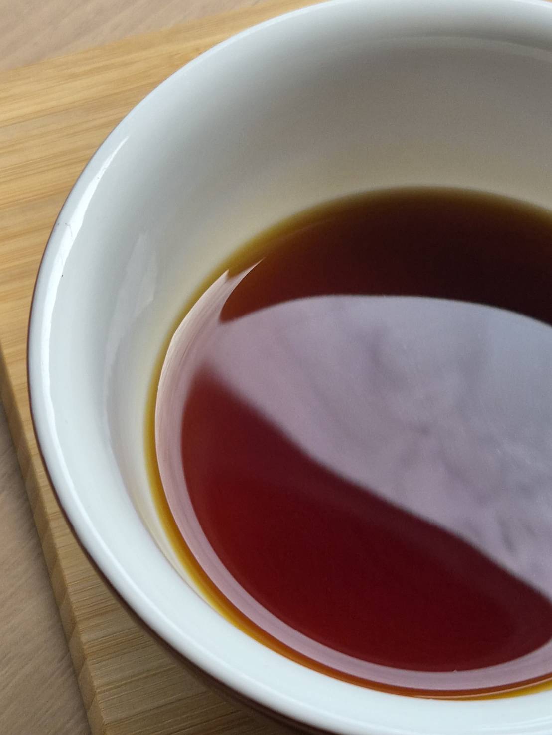 Dark brewed coffee in a white ceramic bowl on wood